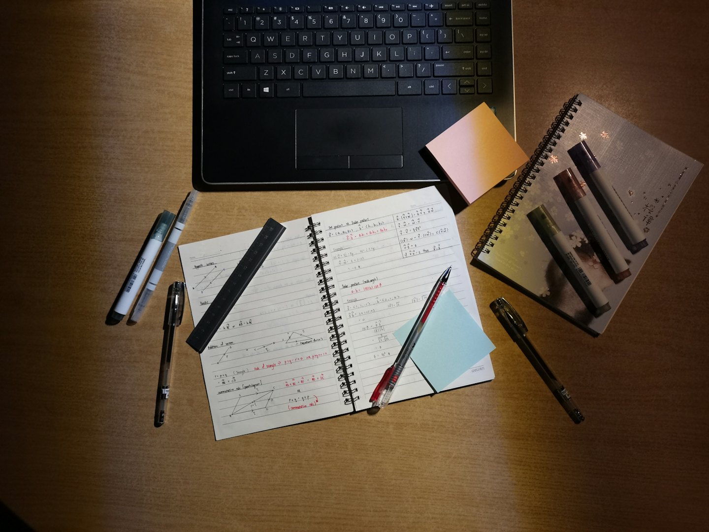 Usługi Otwarty laptop i notatnik z zadaniami matematycznymi na drewnianym biurku.